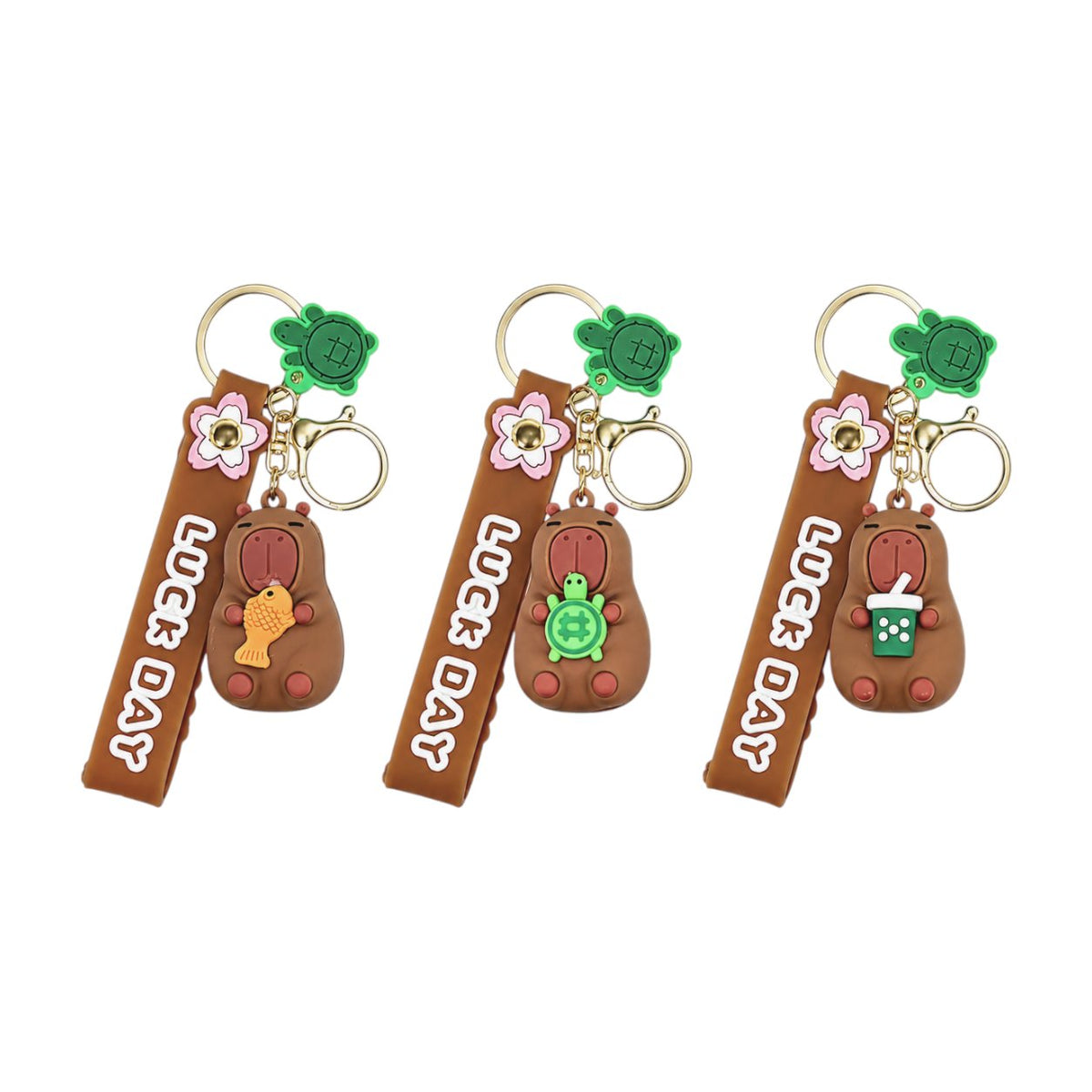 Tre portachiavi a forma di capibara marrone con fiori rosa, accessori verdi e anellino dorato, stile kawaii