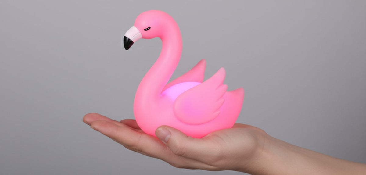 Lampada punto luce flamingo rosa held in hand with white beak details on gray background