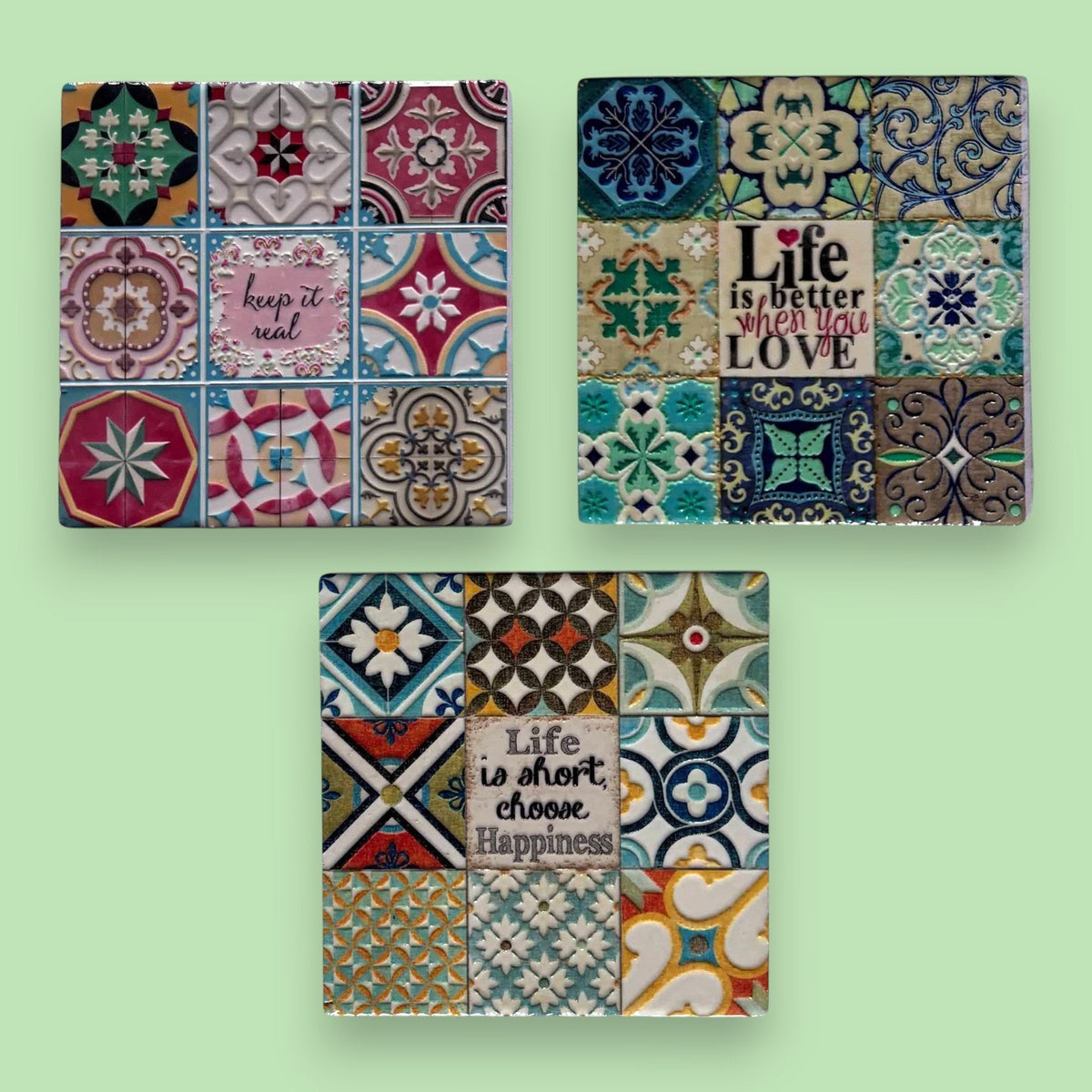 Tre sottobicchieri in maiolica con piastrelle decorate. Motivi geometrici e floreali colorati. Frasi motivazionali: "keeps i