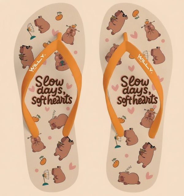 Infradito donna beige con stampa ripetuta di capibara marrone, cuori rosa, arance, fascia arancione e scritta slow days soft 