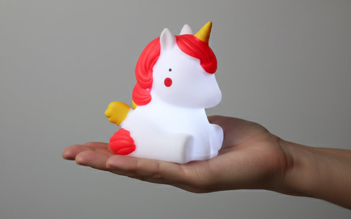 Lampada notturna unicorno bianco con criniera rossa, corno dorato e ali gialle, tenuta in mano