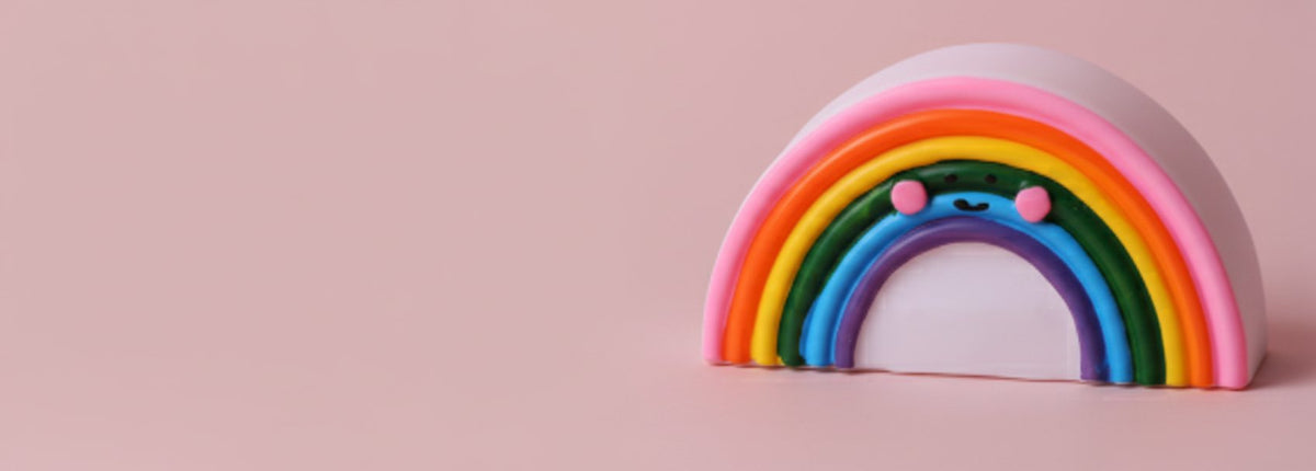 Lampada punto luce a forma di arcobaleno colorato con dettagli rosa su sfondo rosa chiaro