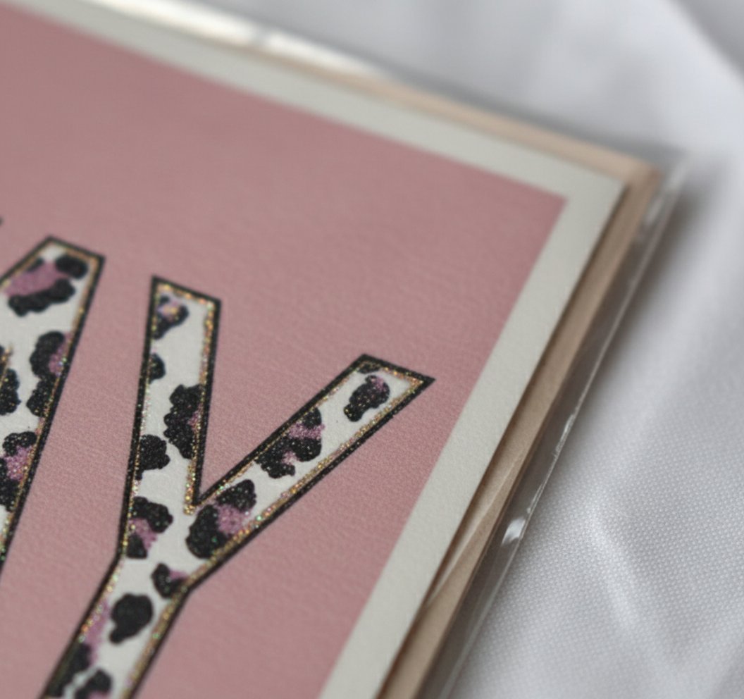 Biglietto auguri rosa con nastro animalier nero e rosa, bordo bianco, design elegante e sofisticato