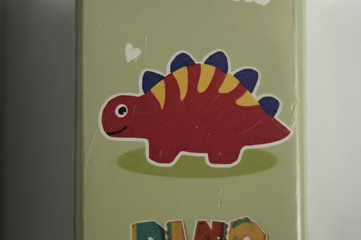 Gomma per cancellare a forma di dinosauro rosso con spine gialle e blu, su sfondo verde chiaro
