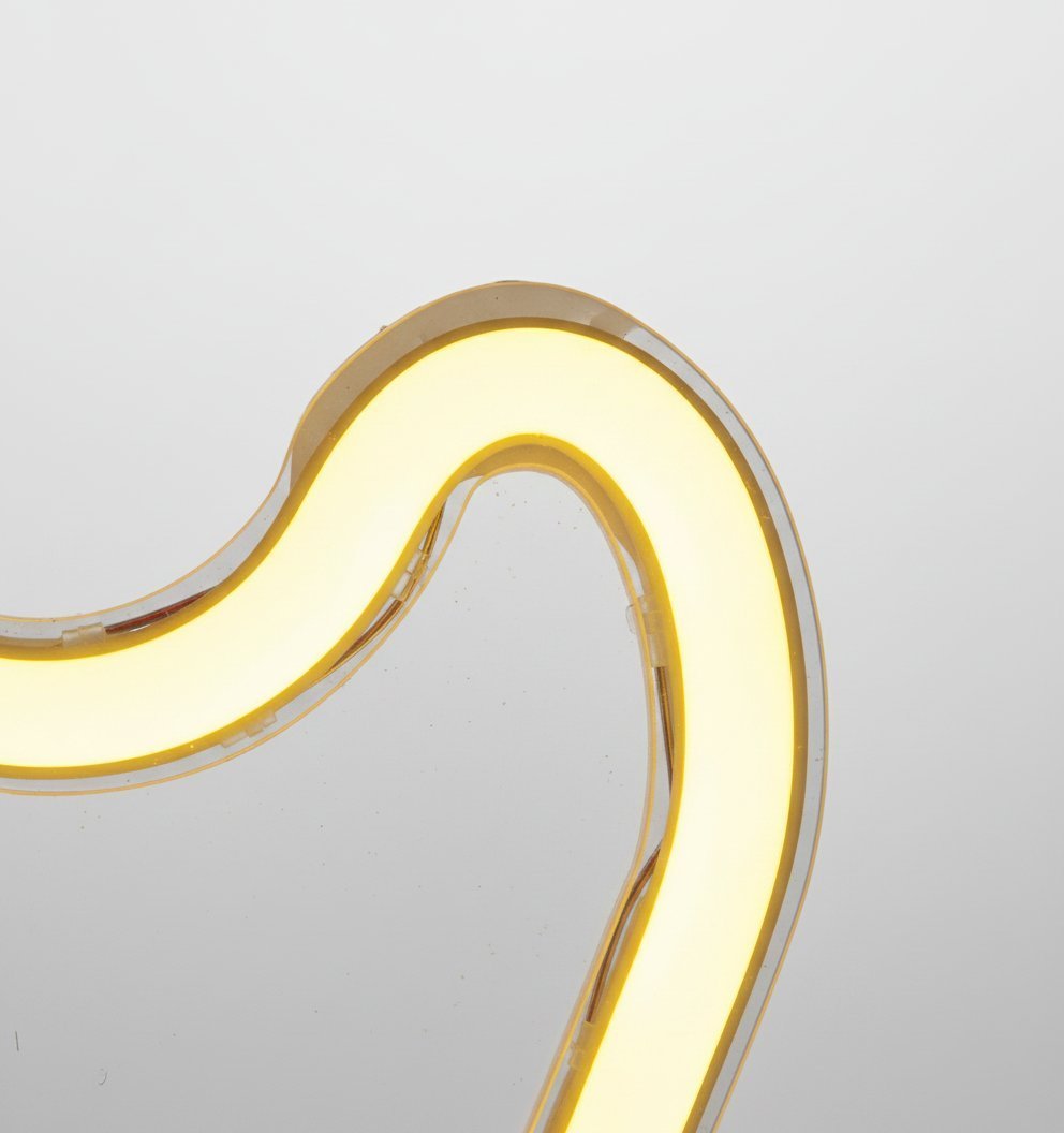 Lampada neon unicorno giallo e bianco a forma di corno luminoso su sfondo grigio