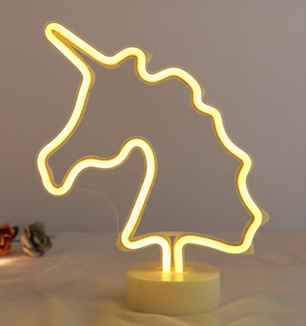 Lampada neon unicorno con tubo luminoso giallo oro, design stilizzato su base bianca, decorazione moderna
