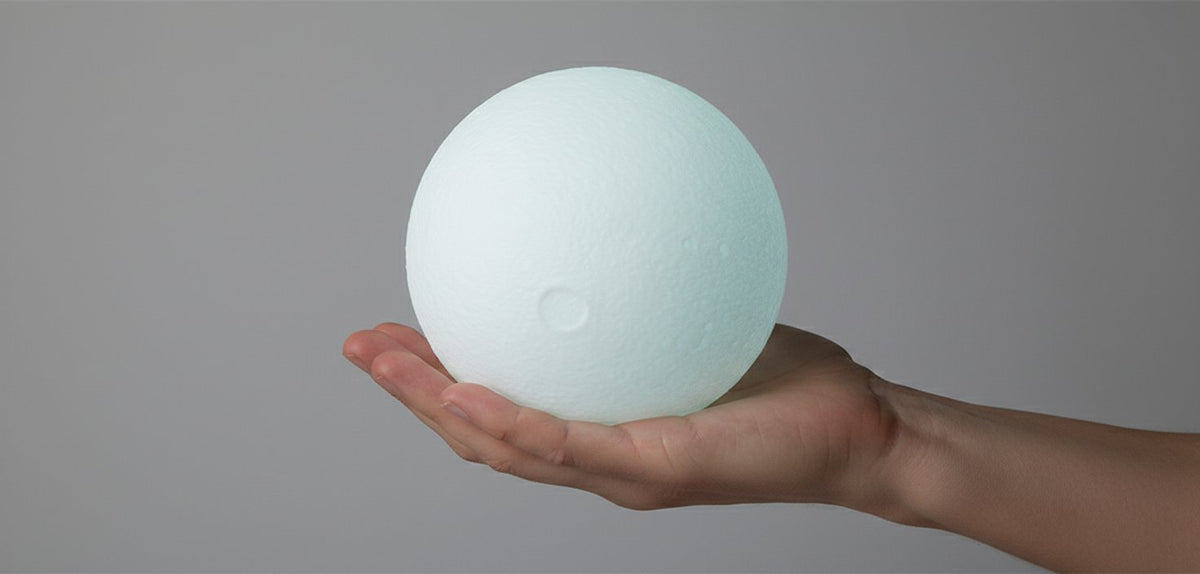 Lampada sferica Moon bianca in mano, design minimalist e moderno su sfondo grigio