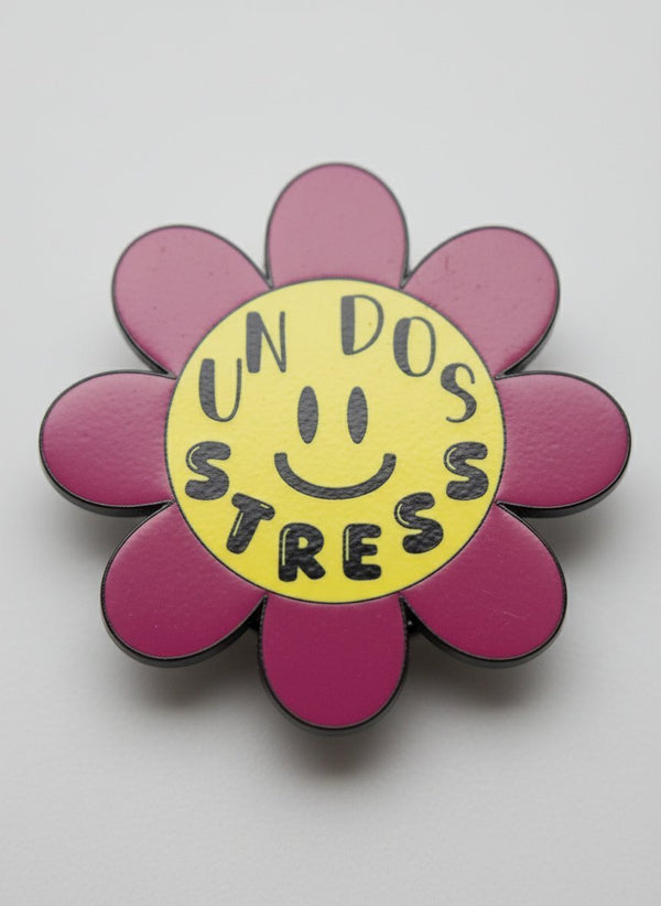 Spilla stress a forma di fiore rosa con centro giallo e smile, scritta "Un Dos Stres